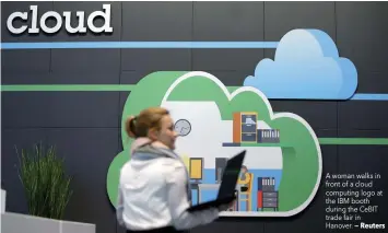  ?? — Reuters ?? A woman walks in front of a cloud computing logo at the IBM booth during the CeBIT trade fair in Hanover.