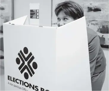  ?? JONATHAN HAYWARD, THE CANADIAN PRESS ?? Premier Christy Clark peeks over the top of the voter shield as she marks her ballot during advance voting on May 8, 2013. Her victory in that election surprised most pundits.