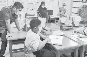  ?? — Gambar Bernama ?? LAWATAN: Radzi melihat adik Muhammad Adib Jaswan membaca Al-Quran braille semasa mengadakan lawatan sempena pembukaan semula sesi persekolah­an secara bersemuka di Sekolah Kebangsaan Putrajaya Presint 18 (1), Putrajaya semalam.