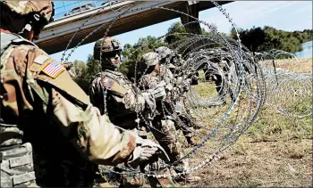  ?? JOHN MOORE/GETTY ?? U.S. Army active duty troops from Ft. Riley, Kan., lay out razor wire along the Rio Grande at the U.S.-Mexico border.
