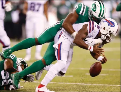  ?? AP PHOTO / KATHY WILLENS ?? Buffalo Bills quarterbac­k Tyrod Taylor, bottom, fumbles the ball as he is hit by New York Jets outside linebacker Jordan Jenkins (48) during the second half of an NFL football game, Thursday in East Rutherford, N.J. The Jets recovered the ball.