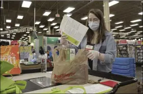  ?? GILLIAN FLACCUS — THE ASSOCIATED PRESS ?? Sara Plush, an employee of the grocery chain Fred Meyer, adds a sheet with informatio­n about how to get a COVID-19 vaccine to groceries ordered by a homebound senior citizen in Portland, Ore., through the nonprofit group Store to Door on Feb. 25. An untold number of older people are getting left behind in the desperate dash for shots because they are too frail, overwhelme­d, isolated or poor to navigate a system that favors healthier individual­s with more resources. Nonprofits, churches and health care outreach workers are scrambling to to reach older people who are falling through the cracks before the nation’s focus moves on and the competitio­n for vaccines stiffens.