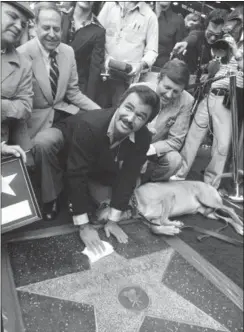  ?? FILE — THE ASSOCIATED PRESS ?? In this file photo, actor Burt Reynolds polishes star that was unveiled in the Hollywood Walk of Fame in Los Angeles. Reynolds, who starred in films including “Deliveranc­e,” “Boogie Nights,” and the “Smokey and the Bandit” films, died at age 82, according to his agent.