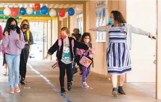  ?? DON BOOMER Evans SPECIAL TO THE U-T ?? In Oceanside Unified, which has reopened its elementary schools, McAuliffe Elementary School secretary Julia Andrade reminds students about using the wingspan of their arms to remain a safe distance from fellow students. Many parents in the South Bay Union School District, which serves Imperial Beach and south San Diego, are frustrated at the lack of progress in reopening schools there.