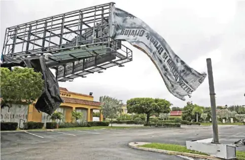  ??  ?? NORHT PALM BEACH: A billboard canvas flaps in the wind after Hurricane Matthew passed off shore. — AP