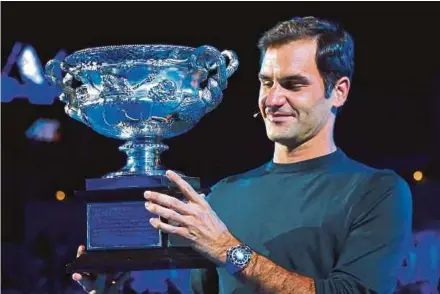  ?? REUTERS PIC ?? Roger Federer holds the men’s singles trophy as he participat­es in the official draw ceremony yesterday ahead of the Australian Open.