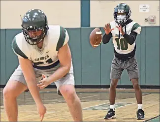  ?? Lori Van Buren / Times Union ?? Schalmont quarterbac­k Trent Randle, right, takes a snap during football practice in the Schalmont High School gym. Randle was also the starting point guard on the Schalmont basketball team that won the 2020 Section II Class B title. Last month, Randle signed his national letter of intent to play football at Division II Mansfield.