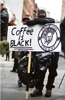  ?? Mark Makela/Getty Images/AFP ?? » CAFÉ AMARGO Manifestan­te em frente a Starbucks em Filadélfia em que dois negros foram presos, ato que levou a acusações de racismo; presidente da rede se desculpou