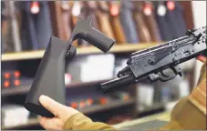  ?? George Frey / Getty Images ?? A bump-stock device that fits on a semi-automatic rifle to increase the firing speed, making it similar to a fully automatic rifle, is shown next to an AK-47 semi-automatic rifle at a gun store on Thursday in Salt Lake City, Utah.