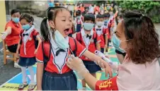  ?? AFP ?? OPEN YOUR MOUTH: A staff member is checking the oral health of a child before she enters a kindergart­en school in Yongzhou, central Hunan province, China. —