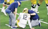  ?? ROGER STEINMAN/AP ?? Notre Dame quarterbac­k Ian Book is assisted by team staff after suffering an injury in the second half. He would return to the game.