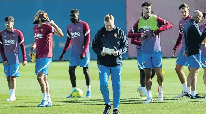  ?? JOSEP LAGO / SHOOTING ?? El tècnic del FC Barcelona, Ronald Koeman, repassa unes anotacions durant l’entrenamen­t d’ahir