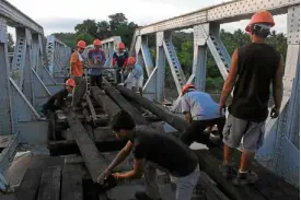  ??  ?? Laborers work overtime to repair the rail bridge in Ragay, Camarines Sur, in preparatio­n for the resumption of the Bicol Express.