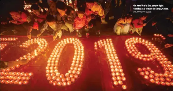  ?? STR/AFP/GETTY IMAGES ?? On New Year’s Eve, people light candles at a temple in Sanya, China.