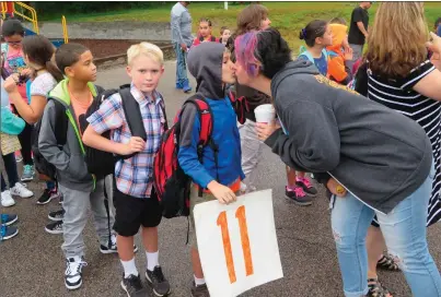  ?? Photo by Joseph B. Nadeau ?? Students stand in line before the start of school at Bernon Heights Elementary School in Woonsocket on Wednesday, as mom Lauri Whelan gives a kiss goodbye to her son, Rian Losardo, before he starts fourth grade.