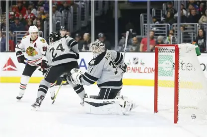  ??  ?? LOS ANGELES: Chicago Blackhawks right wing Patrick Kane, left, scores a goal past Los Angeles Kings defenseman Derek Forbort, center, and goalie Peter Budaj, right, during the first period of an NHL hockey game Saturday, in Los Angeles. — AP