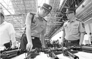  ??  ?? In this file photo, China embassy’s military attaches of the People’s Liberation Army inspect rifles donated by their government to the Philippine military, with a tarpaulen (background right) emblazoned with logos of the Philippine defence department...