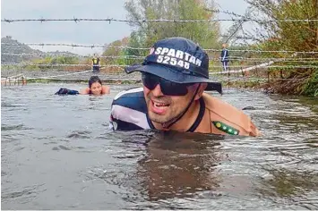  ?? Fotos: Schwalber ?? Thomas Högg beweist hier Nehmerqual­itäten. Er schwimmt in eiskaltem, dreckigem Wasser unter einem Stacheldra­htsystem hin durch. Klar, dass man im Blickfeld einer Frau nicht aufgeben will.