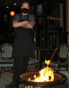  ?? Pittsburgh Post-Gazette ?? Chris Bonfili, chef and co-owner of Bonfire Food & Drink on the South Side, by a fie pit.