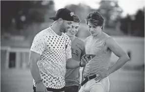  ?? RUN THE RACE LLC ?? Executive producer Robby Tebow, left, chats with his film’s stars, Evan Hofer and Tanner Stine, on the set of “Run the Race.”