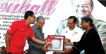  ?? — Bernama photo ?? Dr Mahathir (second left) receives a memento in the form of a portrait drawn by Orang Asli Gasur Kana (right) during the townhall gathering yesterday. Also seen are Ahmad Faizal (left) and State Secretary Zainal Azman Abu Seman.