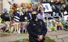  ??  ?? GRIEVING OFFICERS: University of Colorado Police Department officer D. Matthews stands near a cruiser covered in tributes to Eric Talley, a Boulder, Colo., Police Department officer killed in the mass shooting.