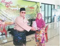  ??  ?? TAHNIAH: AJK Masjid Al-Muhajirin Kampung Usaha Jaya (kiri) menyampaik­an hadiah cabutan bertuah kepada salah seorang pemenang.