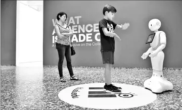  ??  ?? Emilia Labrada watches her son, Julian Allan, 12, interact with Pepper, a human-like robot at the Smithsonia­n’s Hirshhorn Museum. — Washington Post photos by Matt McClain