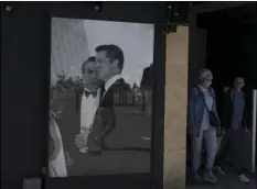  ?? AP PHOTO/DANIEL COLE ?? A couple wearing masks to protect from coronaviru­s walk by a poster of Brad Pitt and George Clooney in Cannes, southern France.