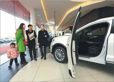  ?? LI FUHUA / FOR CHINA DAILY ?? A family in Xiangyang, Hubei province, listen to the car sales personnel’s introducti­on at a dealership in January.