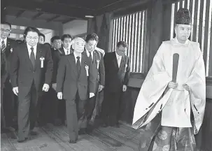  ?? — Gambar AFP ?? BANGKIT KONTROVERS­I: Seorang sami Shinto mengiringi anggota perundanga­n Jepun yang melawat Tokong Yasukuni di Tokyo, semalam.