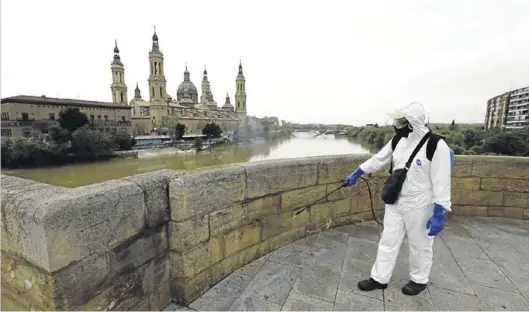  ?? JAIME GALINDO ?? Un funcionari­o de FCC realiza labores de desinfecci­ón, ayer, el puente de Piedra de la capital aragonesa.