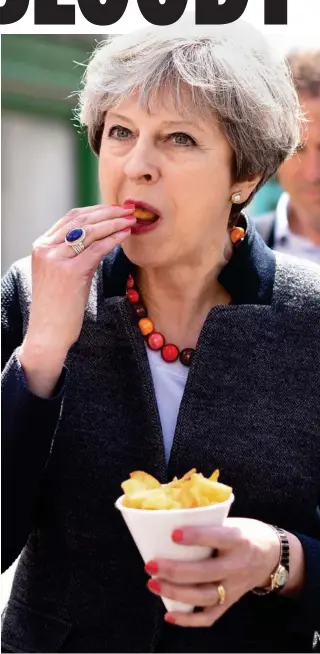  ??  ?? Snack: Mrs May enjoys a cone of chips in Mevagissey, Cornwall, yesterday