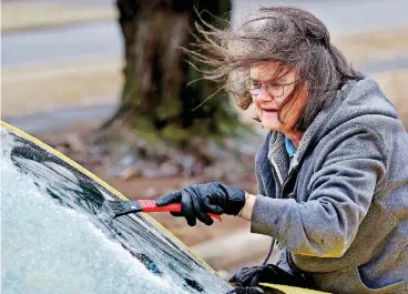  ?? [PHOTO BY JIM BECKEL, THE OKLAHOMAN] ?? Linda Lane scrapes ice from her car’s windshield in the parking lot of the Tinker Area YMCA on Tuesday morning.