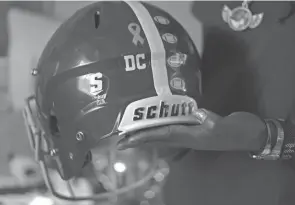  ?? ?? Knight holds a KIPP Columbus football helmet with a “DC” sticker on it in memory of her son on Oct. 11 at her home in Columbus, Ohio. Calhoun was shot and killed on Jan. 3 at the age of 19 and is one of a record-breaking number of homicide victims this year.