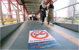  ??  ?? ... A notice with a no-smoking sign and the fines imposed is displayed on a pedestrian bridge in Kuala Lumpur in conjunctio­n with the launch of the KL Free from Cigarette Smoke campaign yesterday.