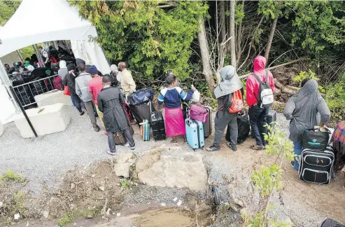  ?? GEOFF ROBINS / AFP / GETTY IMAGES ?? A long line of asylum seekers wait to illegally cross the Canada-U.S. border near Champlain, N.Y., last August. In June, the Immigratio­n department recorded just 1,263 “RCMP intercepti­ons” — less than half what it was in April.