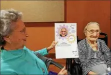  ?? DAN SOKIL — DIGITAL FIRST MEDIA ?? Anna Clapsaddle sits next to a portrait and biography indicating her 1911 birthday held by her daughter Carrie at a luncheon for centenaria­ns hosted by the Montgomery County Office of Aging and Adult Services on Thursday.