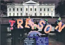  ?? BLOOMBERG ?? Demonstrat­ors hold illuminate­d letter signs that read ‘treason’ outside the White House. n