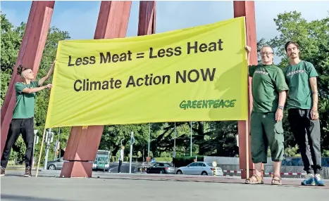  ??  ?? Greenpeace activists hold a banner reading ‘less meat : less heat, climate action now’, during a protest prior to the publicatio­n of IPCC special report on climate change and land on August 8, in Geneva. AFP