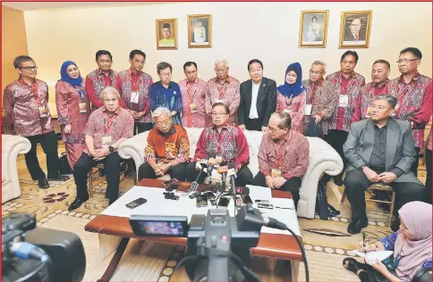  ??  ?? Abang Johari (seated centre) announces his new cabinet line-up in the presence of his team and State Secretary Tan Sri Datuk Amar Mohamad Morshidi Abdul Ghani (seated right). — Photo by Tan Song Wei