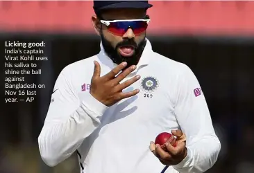  ??  ?? Licking good: India’s captain Virat Kohli uses his saliva to shine the ball against Bangladesh on Nov 16 last year. — aP