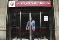  ??  ?? MILAN: A man waits for the sliding doors to open to exit a Monte dei Paschi di Siena bank branch. — AP