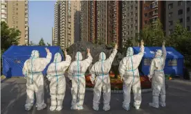  ?? Photograph: VCG/Getty Images ?? Volunteers wearing personal protective equipment (PPE) gesture at a makeshift nucleic acid testing site in Beijing