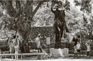  ?? Billy Calzada / Staff photograph­er ?? Visitors are shown near a statue of John William Smith, a messenger during the 1836 Siege of the Alamo, on the Alamo grounds. The major partners in a planned overhaul and expansion of the Alamo site have said they’re committed to moving forward, despite the decision on the Cenotaph.