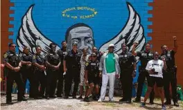  ??  ?? Houston police officers pose for a photograph in front of the mural honoring George Floyd Jr. on Winbern Street in Third Ward.