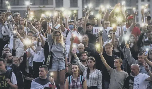  ?? PICTURE: GETTY IMAGES ?? 0 Belarus opposition supporters raise their mobile phones with torches on during a symbolic minute of silence near the state TV and radio company