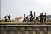  ?? WONG MAYE-E / AP ?? North Koreans walk while some cycle past a factory dome with Korean words painted on its side which read “First priority: self developmen­t” at the end of a work day Thursday in Hamhung. The U.S. plans to bar most Americans from visiting the country.