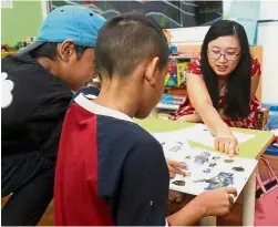  ??  ?? Staying positive: The Star reporter Hanis Zainal going through a picture book with the two brothers at Yayasan Chow Kit.