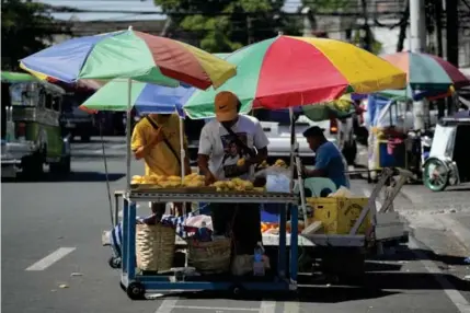  ?? AP PHOTO ?? ▪ Vendors arrange mangoes under umbrellas to shield them from the scorching sun in Quezon City.